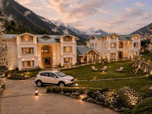 a white car parked in front of a large house at The Riviera Hotel Pahalgam in Pahalgām