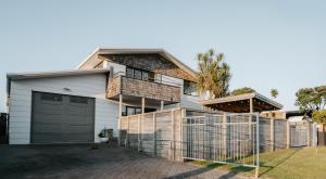 a house with a garage and a fence at Waterfront location with estuary outlook and ocean beach access - sleeps 19 in Pukehina