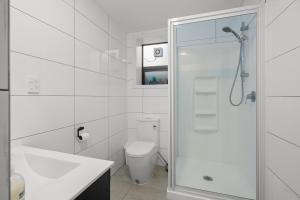 a white bathroom with a shower and a toilet at Waterfront location with estuary outlook and ocean beach access - sleeps 19 in Pukehina +28 photos