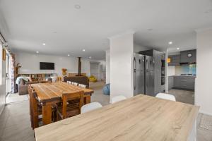 a kitchen and living room with a wooden table and chairs at Waterfront location with estuary outlook and ocean beach access - sleeps 19 in Pukehina
