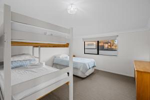a bedroom with two bunk beds and a desk at Waterfront location with estuary outlook and ocean beach access - sleeps 19 in Pukehina
