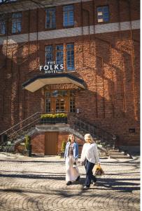 two women walking in front of a building at The Folks Hotel Konepaja in Helsinki