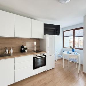 a kitchen with white cabinets and a table at Cool Downtown Apartment in Burgas