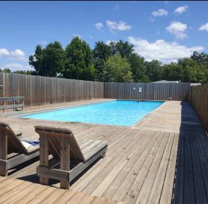 a swimming pool with two chairs and a wooden deck at Mobil home zen élégant in Mimizan