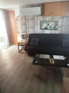 a living room with a black couch and a table at Mobil home zen élégant in Mimizan