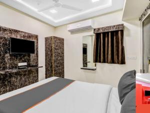 a bedroom with a bed and a tv on the wall at HOTEL Sarovar in Ahmedabad