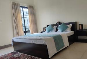 a bedroom with a large bed with blue and green pillows at Bhromor -A Pet-friendly Villa in Raichak