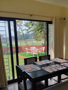 a dining room with tables and chairs and a large window at Bhromor -A Pet-friendly Villa in Raichak