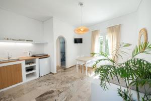 a white kitchen with a table and a potted plant at The White Rose Hotel in Poros