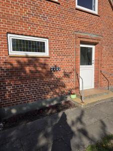 a brick building with a white door and a window at Harknakvej 19BB in Bredebro