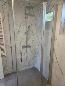 a shower in a bathroom with a marble wall at Harknakvej 19BB in Bredebro +6 photos