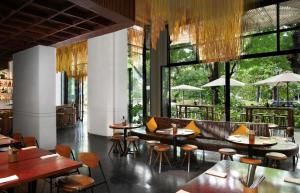 a restaurant with tables and chairs and large windows at Treeline Urban Resort in Siem Reap