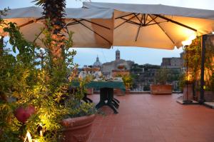 um pátio com uma mesa, um guarda-chuva e plantas em Residenza Maritti Decò Style em Roma