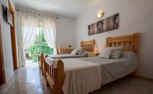 een slaapkamer met 2 bedden en een raam bij Hostal Sango Sierra de las Nieves in Alozaina