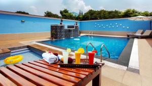 a swimming pool with a wooden bench next to a table at Athena Hotel in Tiruvannāmalai