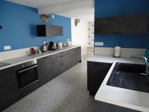 a kitchen with a sink and a blue wall at Chambre Ecuador in Châteaubourg