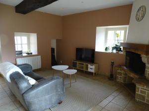 a living room with a couch and a tv at Chambre Ecuador in Châteaubourg
