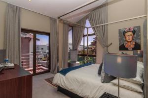 a bedroom with a bed and a desk and a window at Atlantic Waves Guest House in Cape Town +51 photos