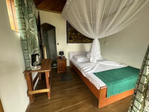 a bedroom with a bed with a canopy at Kenath Paddy Cabin in Bopana