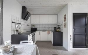 a kitchen with white cabinets and a black door at Comfy Modern Guesthouse in Bankeryd