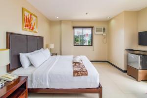a bedroom with a large white bed and a telephone at Main Hotel and Suites Cebu in Cebu City