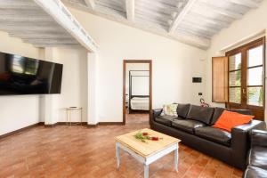 a living room with a black leather couch and a table at Casale Santa Francesca by PosarelliVillas in Campiglia dʼOrcia