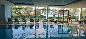 a woman standing next to a swimming pool with chairs at Enidor Wellness Apartman in Siófok