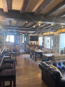 a restaurant with leather furniture and tables and chairs at The Kings Arms Pub in Stratton on the Fosse