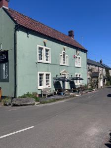 a green house with a bench in front of it at The Kings Arms Pub in Stratton on the Fosse