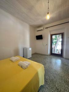 a bedroom with a yellow bed with two towels on it at Camera Ficus in San Teodoro