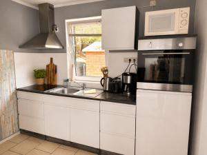 a kitchen with white cabinets and a sink and a microwave at Ferienhaus Rauschenbachmühle in Arnsfeld +10 photos