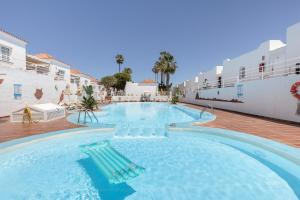 a large swimming pool with chairs in the water at Casa Eri con piscina in Corralejo