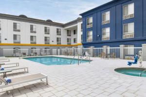 a pool in front of a hotel with tables and chairs at City Express By Marriott Rancho Cucamonga in Rancho Cucamonga