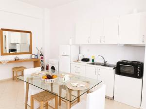 a kitchen with a glass table and white cabinets at Studio Malades, Heraklion in Maládhes