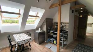 a room with a table and a kitchen with windows at Leśna Kryjówka in Trzebciny