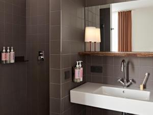 a bathroom with a sink and a mirror at Numa Berlin Weinmeister in Berlin +41 photos