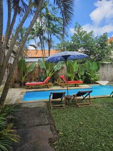 a patio with two chairs and an umbrella next to a pool at Two Brothers Guesthouse in Legian