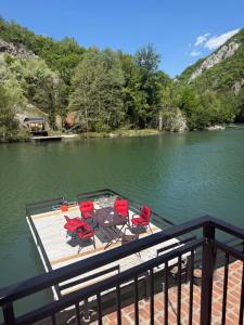 a dock with chairs and a table on the water at Ambijent house Patrijaha Pavla 22 in Železnička Stanica Ovčar Banja