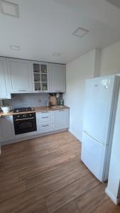 a kitchen with white cabinets and a white refrigerator at Arena apartment in Panevėžys +4 photos