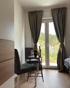 a room with a table with a bottle of wine and a window at Apartmani Tara House in Milekići