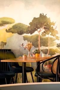 a table with a tree mural on a wall at Hôtel De La Vallée in Dinard