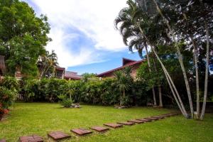 a house with palm trees and a lawn with steps at Mae Rim Lagoon Bed & Bakery in Mae Rim