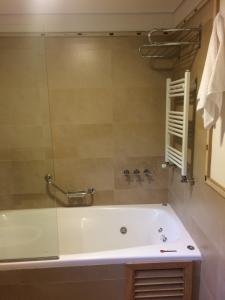 y baño con bañera y ducha acristalada. en Golf y Polo Apartment en San Martín de los Andes