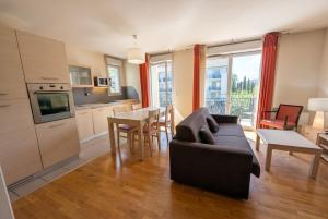 a living room with a black couch and a kitchen at Bright two bedroom duplex apartment in Divonne-les-Bains