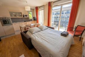 a bedroom with a bed and a kitchen with a window at Bright two bedroom duplex apartment in Divonne-les-Bains