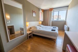 a small bedroom with a bed and a mirror at Bright two bedroom duplex apartment in Divonne-les-Bains