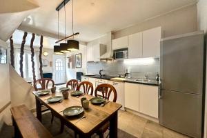 a kitchen with a table with chairs and a refrigerator at Retraite cosy aux portes de la Baie de Somme in Abbeville