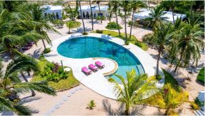 an overhead view of a swimming pool with pink chairs and palm trees at Dhahabu Village - Villa 244 Beachfront stay in Mambrui