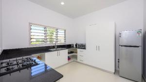 a kitchen with white cabinets and a refrigerator at Dhahabu Village - Villa 244 Beachfront stay in Mambrui +3 photos