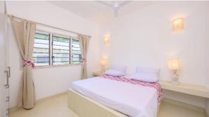 a white bedroom with a bed and a window at Dhahabu Village - Villa 244 Beachfront stay in Mambrui